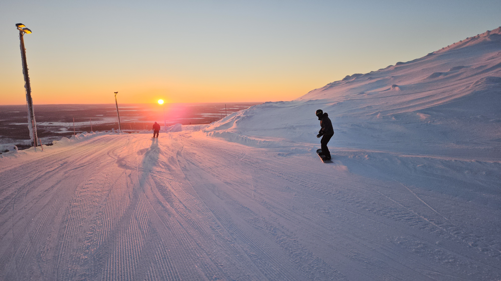 Snowboarder auf Levi Pisten bei Sonnenuntergang
